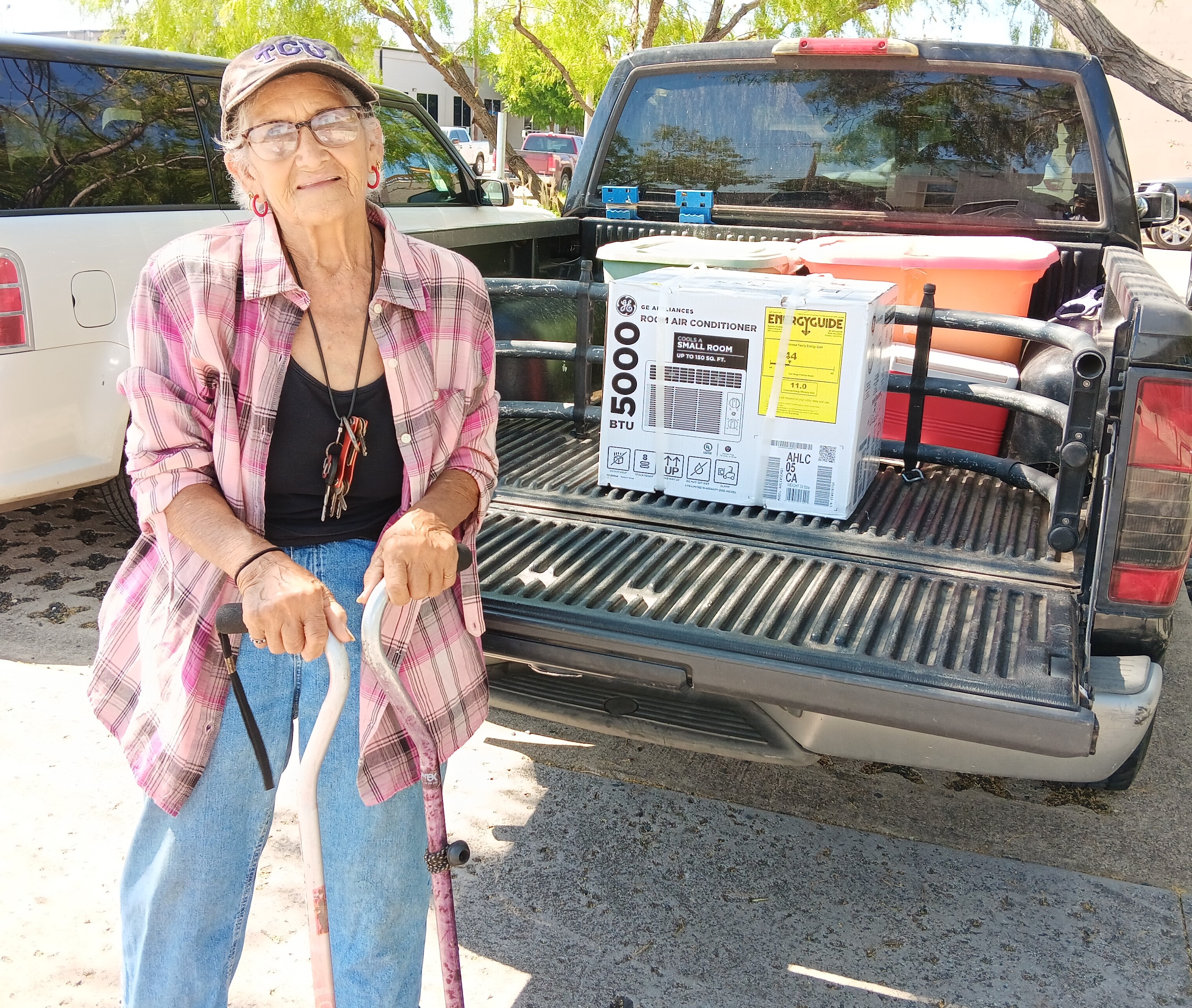 Older adult standing at the foot of her pickup truck that holds an AC unit provided by United Way of Tarrant County.