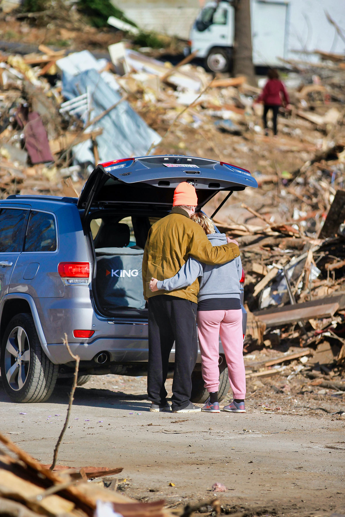 People embracing while surveying damage