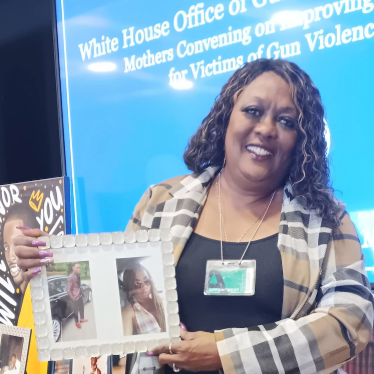 Melinda Hamilton, OSC grantee, holds photos of loved ones she has lost to gun violence.