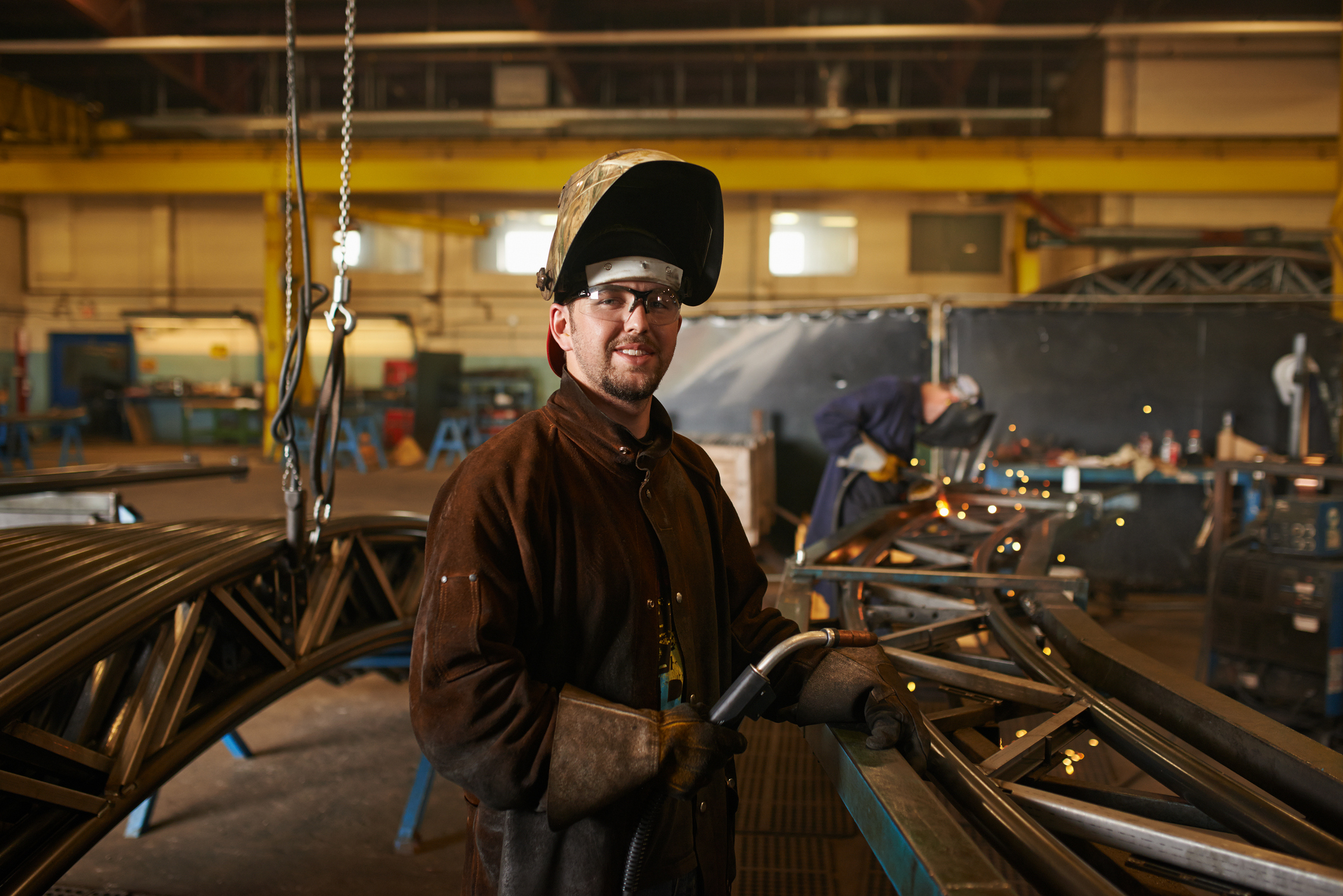 Man in welding gear, working in a welding workshop.