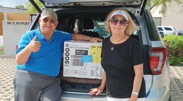 Man and woman in front of the truck of car