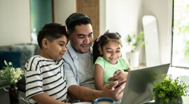 Father searching on the internet with his young son and daughter in their home.