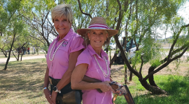 Betsy Price and Linda Halbouty dressed in pink shirts, wearing pearl necklaces. 