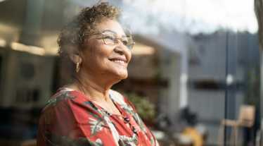 Older woman smiling looking out window.